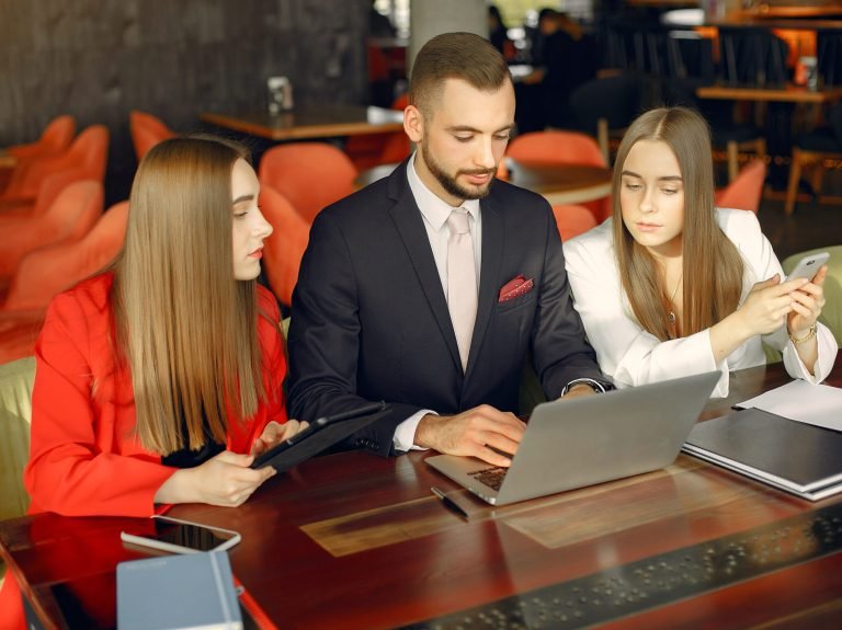 Man and two beautiful women working. People in a cafe. Twins in a elegant suits